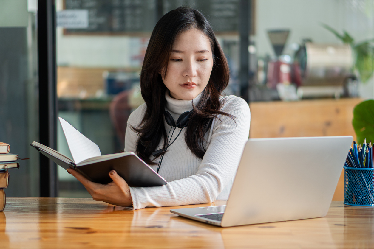 Cybersecurity Student Studying on a Laptop With a Notebook..jpg