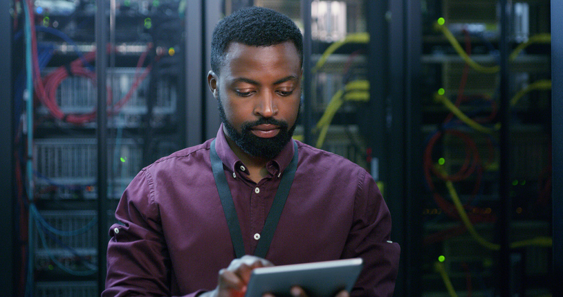 A Cybersecurity Professional Works on a Tablet in a Server Room..jpg