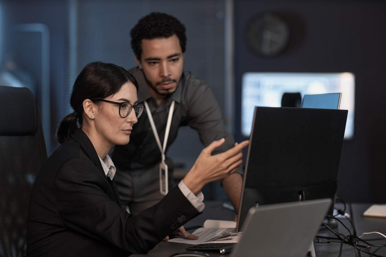 Soc Analyst Looking at a Computer With a Coworker Trying to Solve a Cybersecurity Issue.