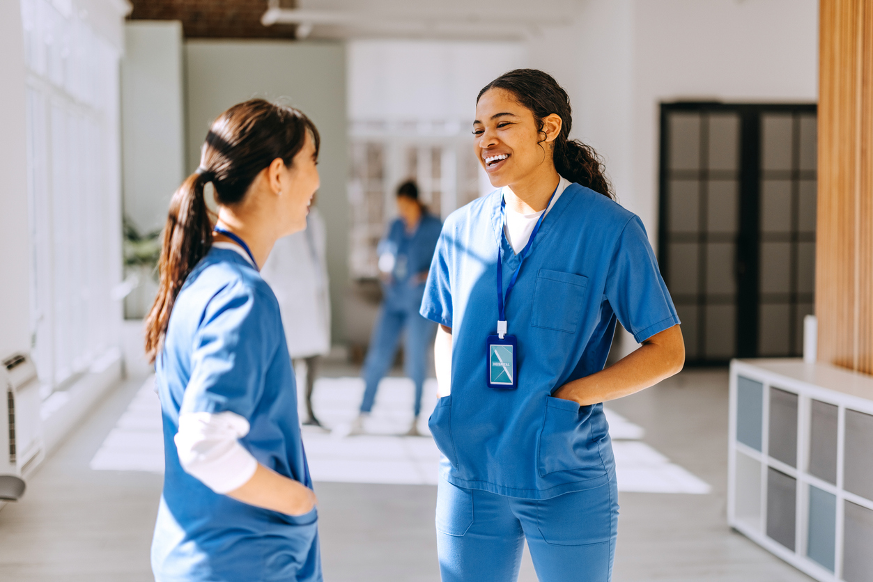 Two nurses talking in a hospital corridor.